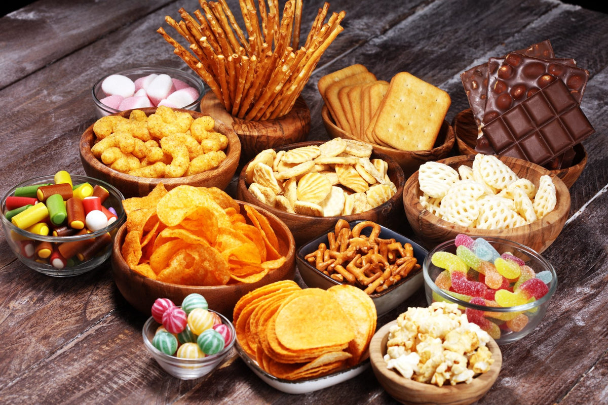 Bowls of chips, biscuits, sweets and chocolate on a wooden table