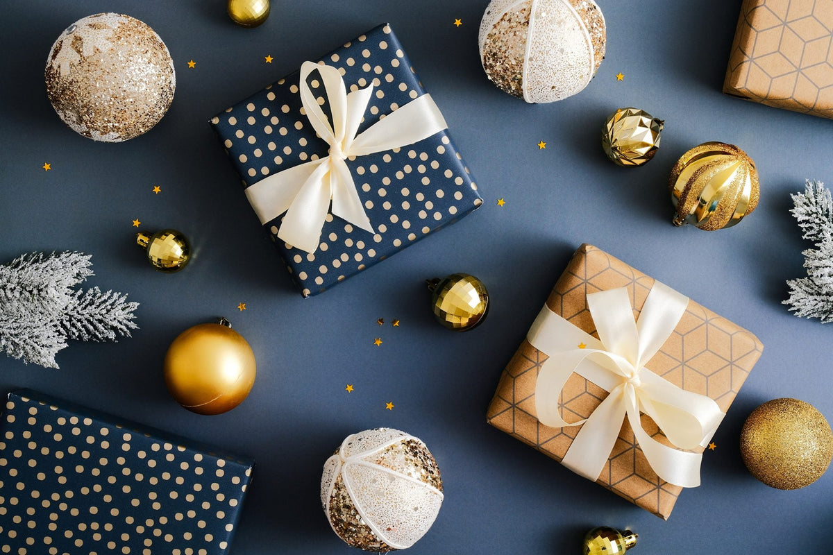 Wrapped gifts and gold Christmas baubles on a navy background
