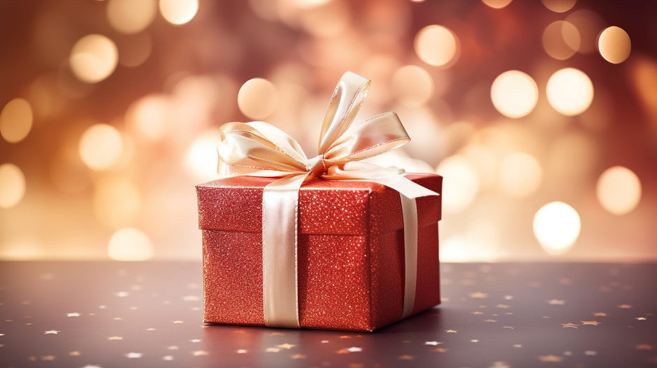 A red gift box with a gold ribbon against warm gold lights