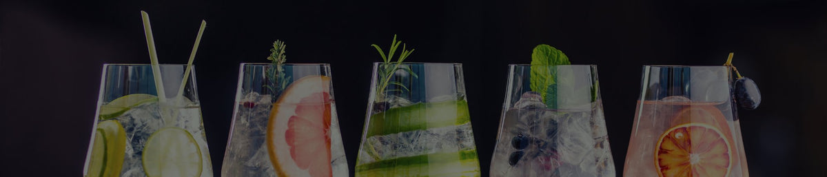 Five garnished gin cocktails with ice against a dark background
