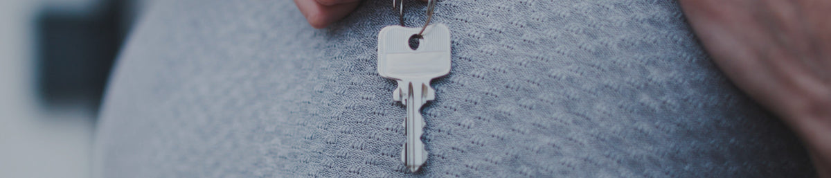 A couple hugging, one holding the keys to their new home