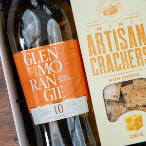 The Hamper Boutique Co’s Glenmorangie Premium Selection Hamper features a bottle of Glenmorangie 10-year-old Scotch and artisan crackers with cheese, all elegantly arranged in a gift box.