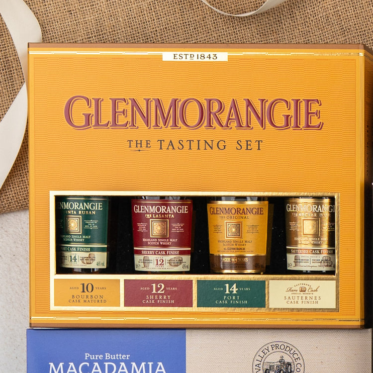 A Glenmorangie Ultimate Tasting Hamper by The Hamper Boutique Co features four mini Scotch whisky bottles with Bourbon, Sherry, Port, and Sauternes cask finishes, presented in a box against a neutral background.