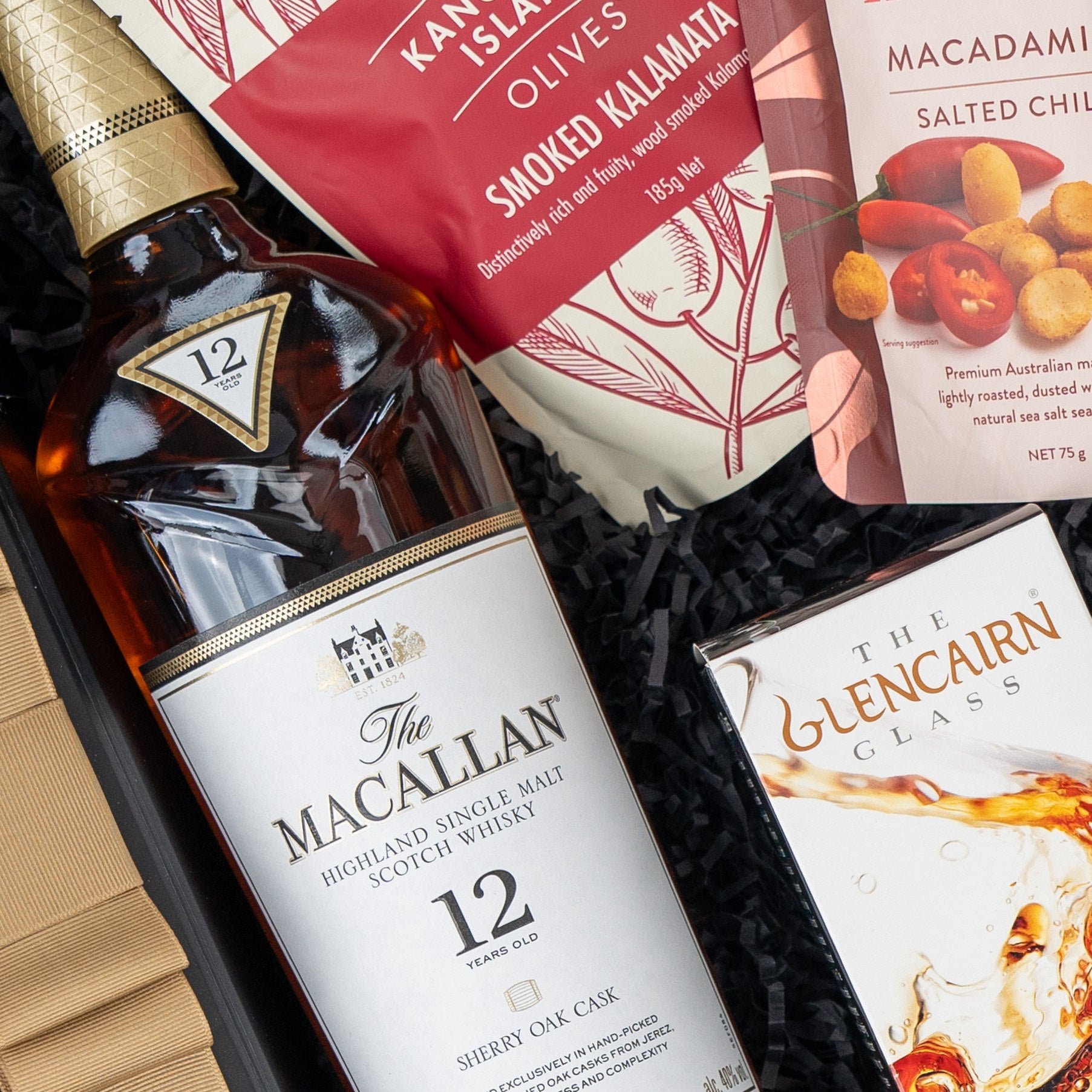 The Hamper Boutique Co's Macallan Indulgence Hamper features The Macallan 12-year-old Scotch, smoked Kalamata olives, salted macadamia nuts, and a Glencairn whisky glass.