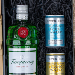 The Hamper Boutique Co’s Tanqueray Delights Hamper features a bottle of Tanqueray gin and two Fever-Tree tonics—Mediterranean and Premium Indian—arranged on black crinkle paper in a gift box.