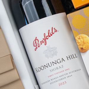A close-up of The Hamper Boutique Co Gourmet Journey Gift Hamper, featuring beige packaging and a partial cookie image.