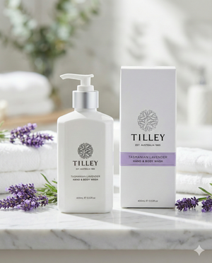 A bottle and box of Tilley Tasmanian Lavender Hand and Body Wash rest on a marble counter with sprigs of lavender and white towels in a bright, clean setting.