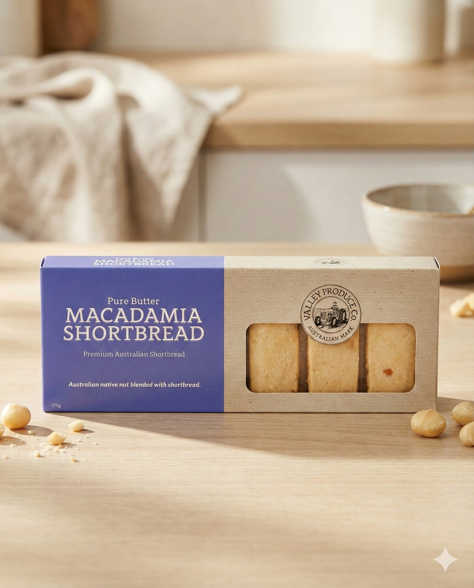 A box of Valley Produce Company Macadamia Shortbread rests on a wooden table, showing three shortbread pieces through its window, with several macadamia nuts scattered nearby.