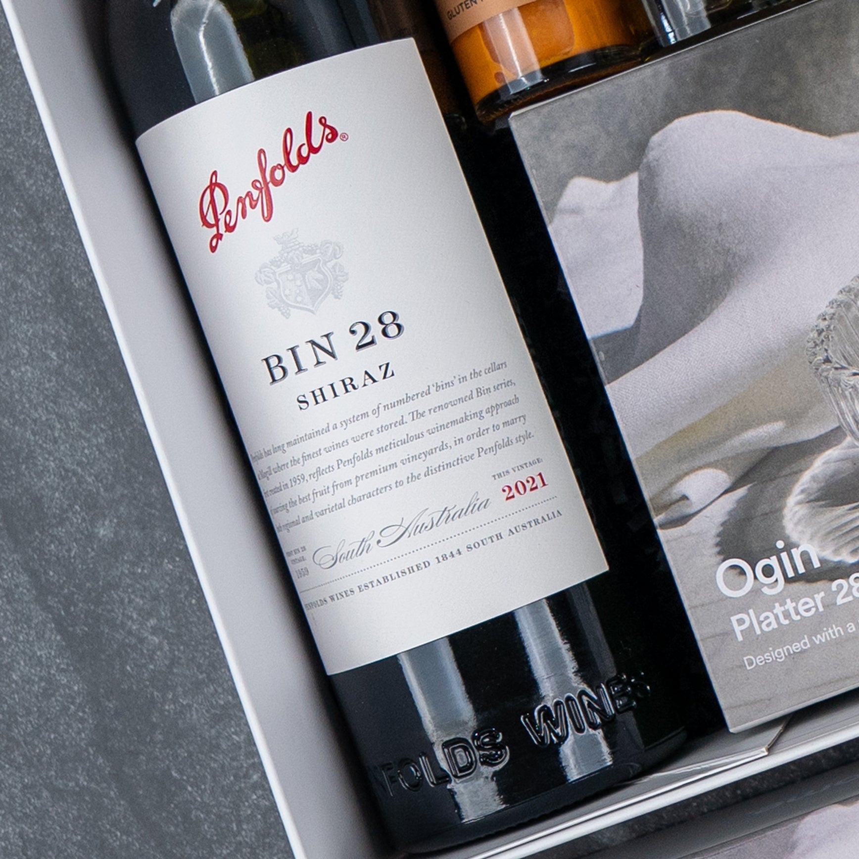 A Luxe Dining Red Wine Hamper by The Hamper Boutique Co is displayed, featuring a gift box with its contents neatly arranged on a gray surface.