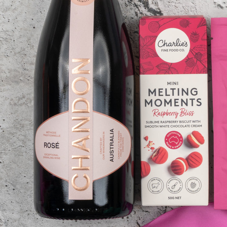 The Hamper Boutique Co's Chandon Rosé Delights Hamper features a bottle of Chandon Rosé and Charlie’s Mini Melting Moments Raspberry Bliss cookies, displayed on a light gray textured surface.