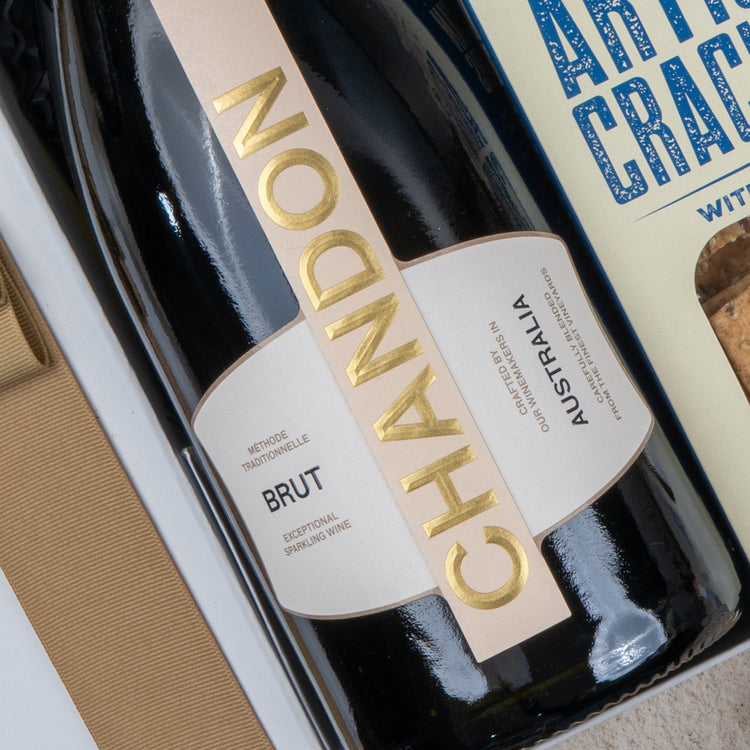 A close-up of The Hamper Boutique Co's Chandon Celebration Hamper, featuring a bottle of Chandon Brut sparkling wine and artisan crackers arranged in an elegant gift box.
