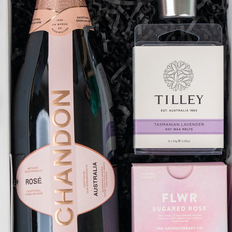 The Hamper Boutique Co’s Chandon Bloom Retreat features Chandon Rosé, Tilley Tasmanian Lavender soy wax melts, and a FLWR Sugared Rose candle, all beautifully arranged on black shredded paper.