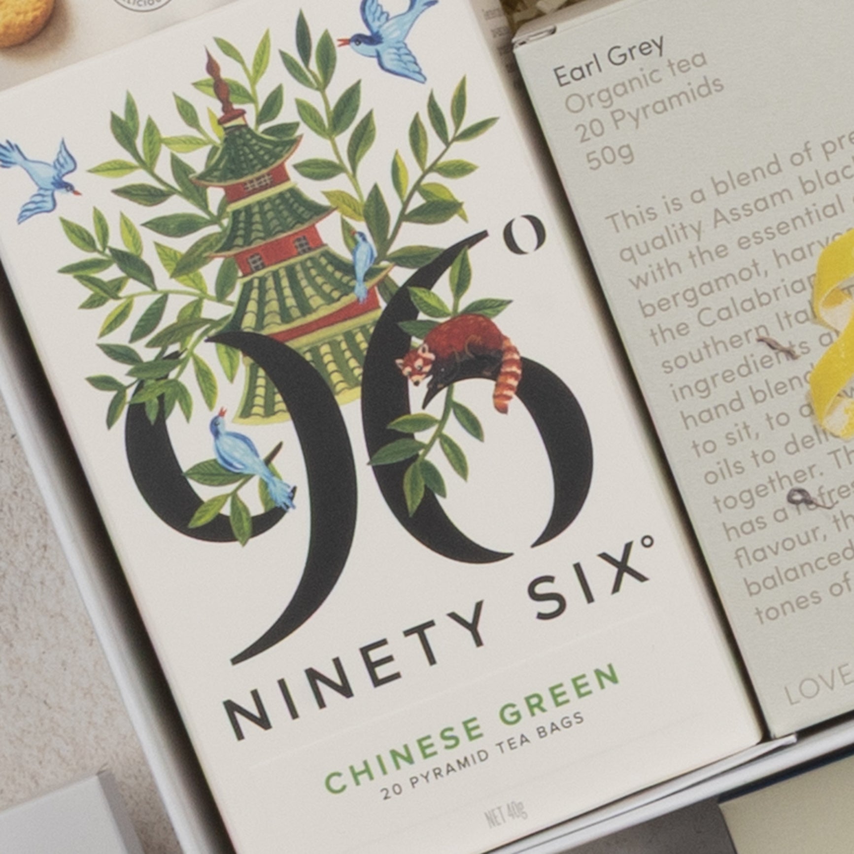 The Tea Time Gourmet Hamper by The Hamper Boutique Co features elegant packaging decorated with a pagoda, birds, and a red panda among greenery. Inside, you'll find 20 pyramid tea bags.
