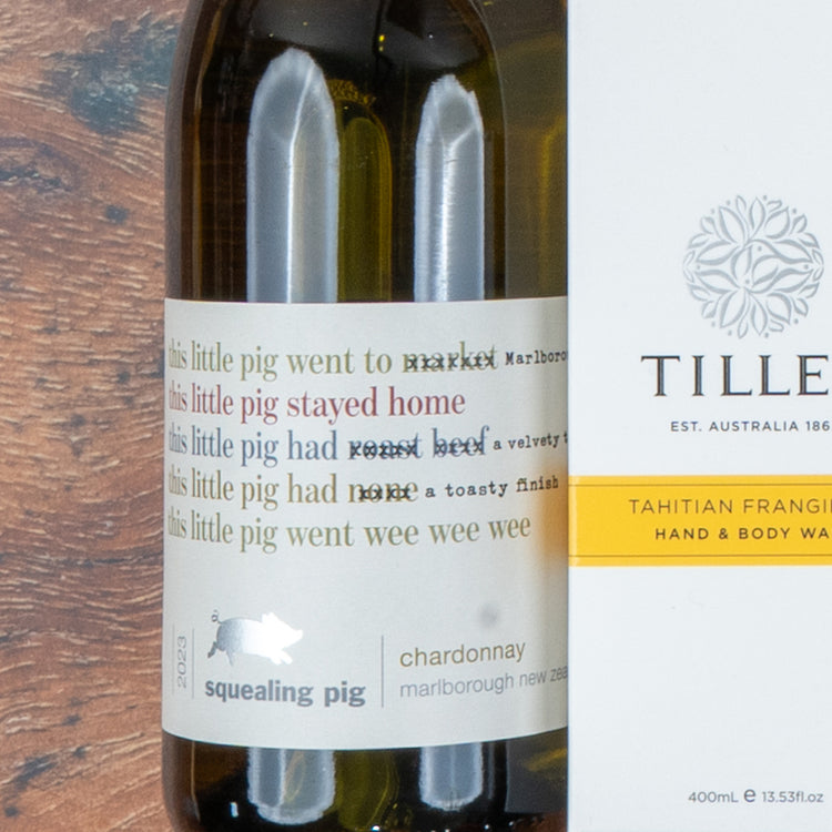 A Chardonnay and Self-Care Hamper from The Hamper Boutique Co, featuring wine and hand wash, sits on a wooden surface.