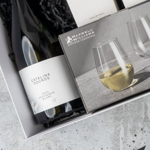 The Hamper Boutique Co’s Elegance and Self-Care Gift Hamper includes Catalina Sounds 2024 Sauvignon Blanc and Maxwell & Williams stemless wine glasses, beautifully presented in a gift box with black crinkle paper.