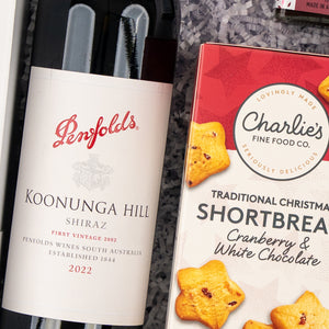 The Hamper Boutique Co's Ruby & Relish Rejoice includes Penfolds Koonunga Hill Shiraz 2022 and Charlies Traditional Christmas Shortbread with cranberry and white chocolate, elegantly presented on shredded paper.