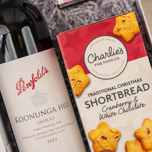 A Merry Shiraz Moments gift hamper from The Hamper Boutique Co featuring Penfolds Koonunga Hill Shiraz 2022 and Charlies Traditional Christmas Shortbread with cranberry and white chocolate, elegantly presented on shredded paper.