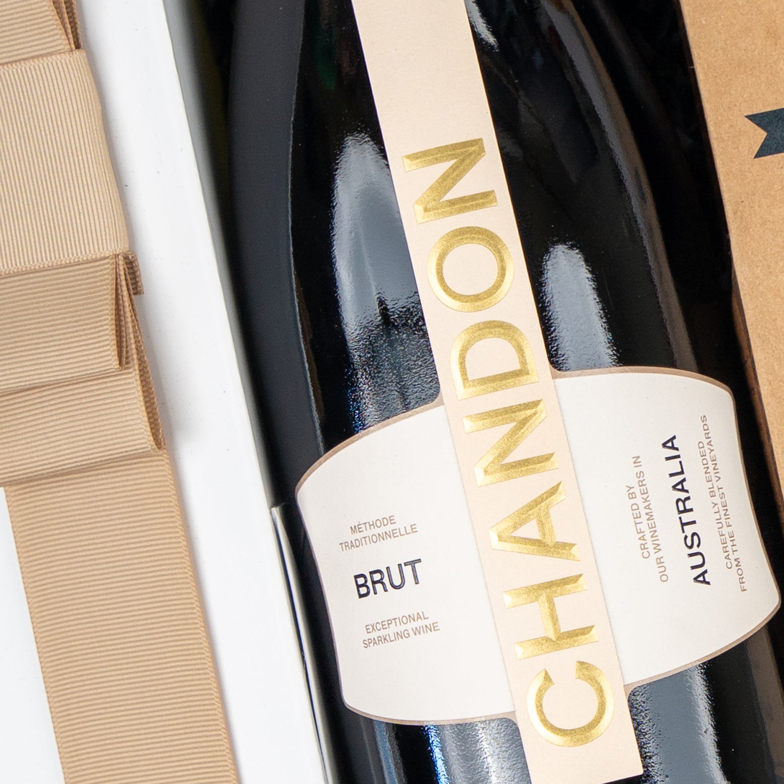 A close-up of The Hamper Boutique Co’s Festive Fizz & Pamper gift, featuring a bottle of sparkling wine with gold and cream labels, plus glimpses of its elegant cardboard packaging and ribbon.
