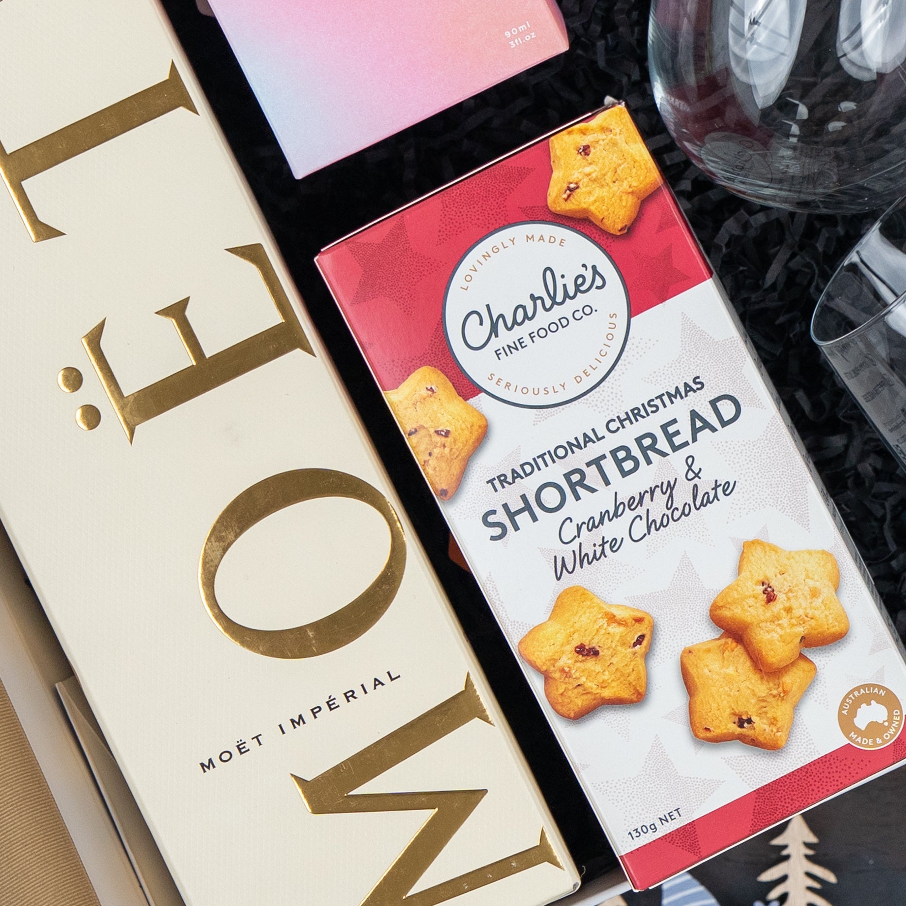 The Hamper Boutique Co's Luxurious Celebrations gift box includes Moët & Chandon champagne and Charlies cranberry & white chocolate shortbread, beautifully presented on a black background.