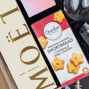 The Hamper Boutique Co's Luxurious Celebrations gift box includes Moët & Chandon champagne and Charlies cranberry & white chocolate shortbread, beautifully presented on a black background.