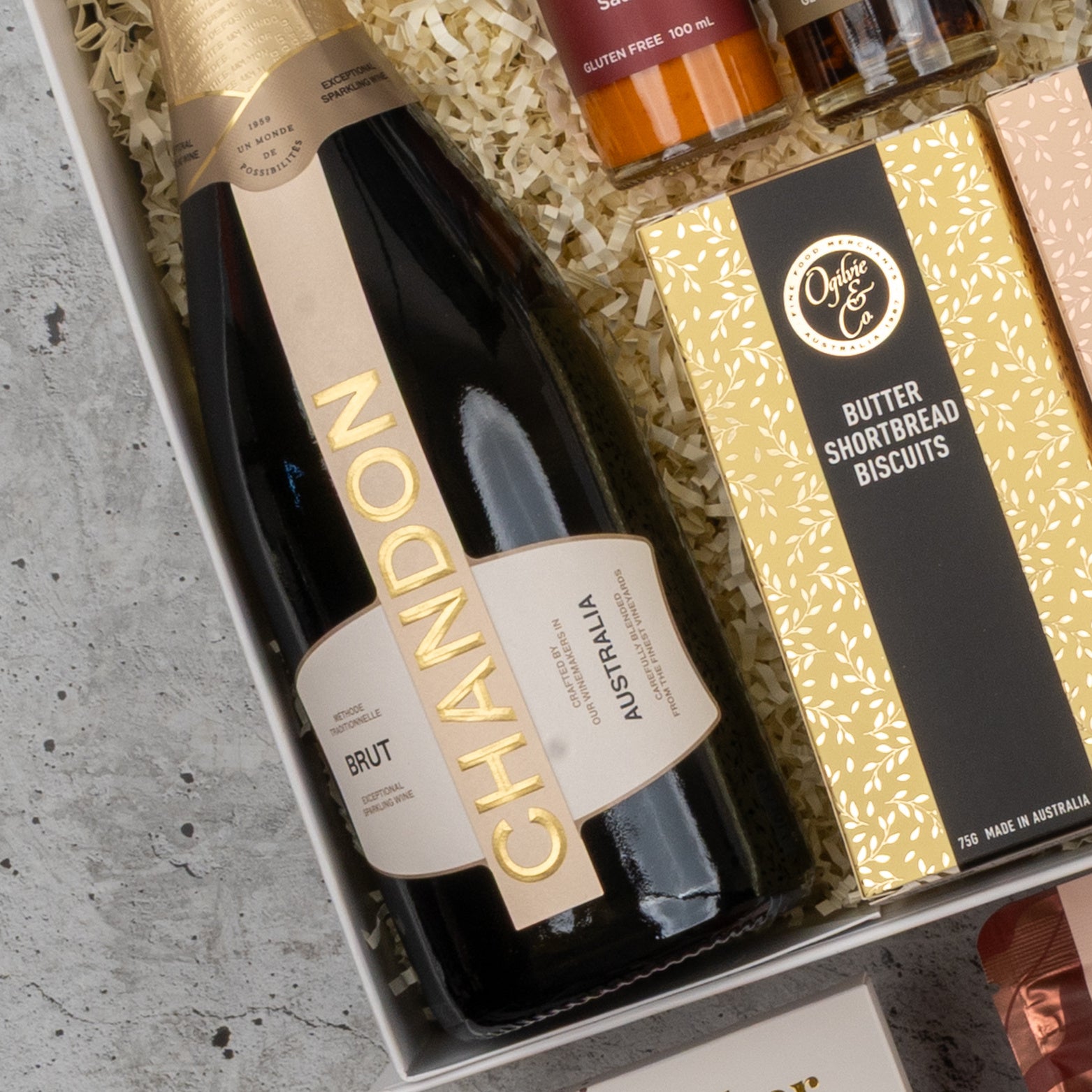 The Hamper Boutique Co Chandon Gourmet Celebration Hamper features a bottle of Chandon Brut sparkling wine and Ogilvie & Co. Butter Shortbread Biscuits, beautifully arranged on shredded paper.