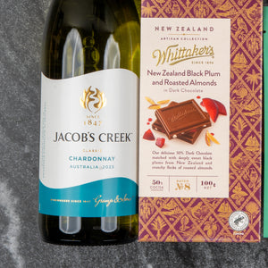 A Wine and Candlelight Hamper from The Hamper Boutique Co is displayed on a dark textured surface.