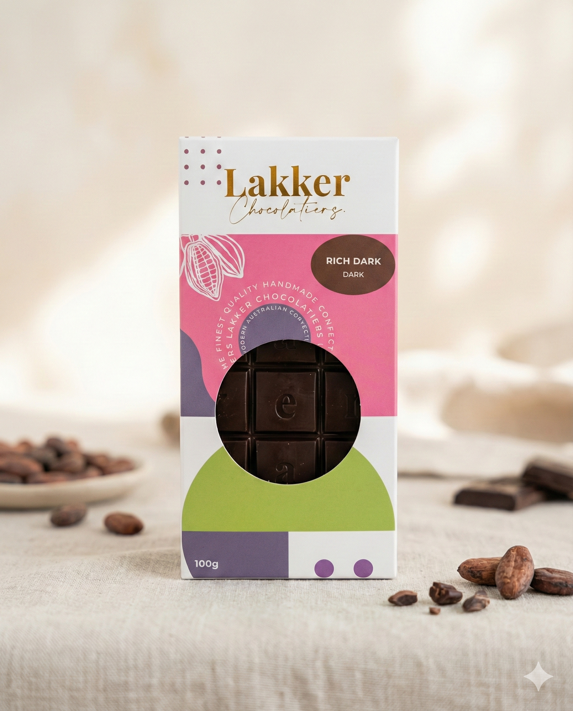 A box of Lakker Chocolatiers Rich Dark Chocolate sits on a light surface, surrounded by cocoa beans and chocolate pieces. The vibrant packaging with geometric shapes showcases the Rich Dark Chocolate bar inside.