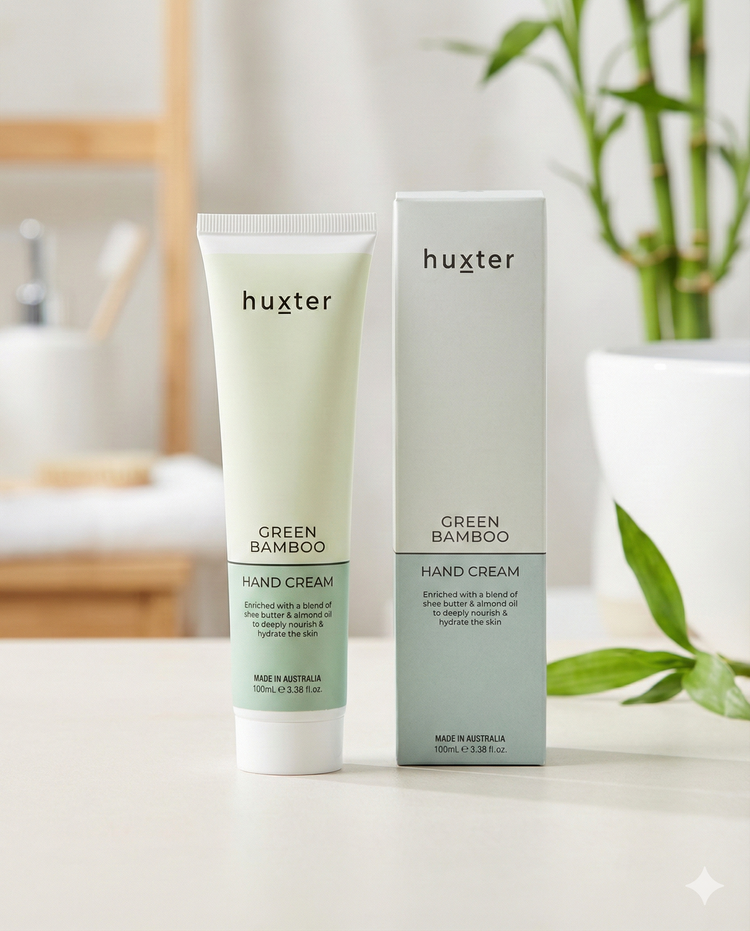 A tube and box of Huxter Green Bamboo Hand Cream are shown on a white surface, accented by bamboo leaves in the background for a fresh, natural look.