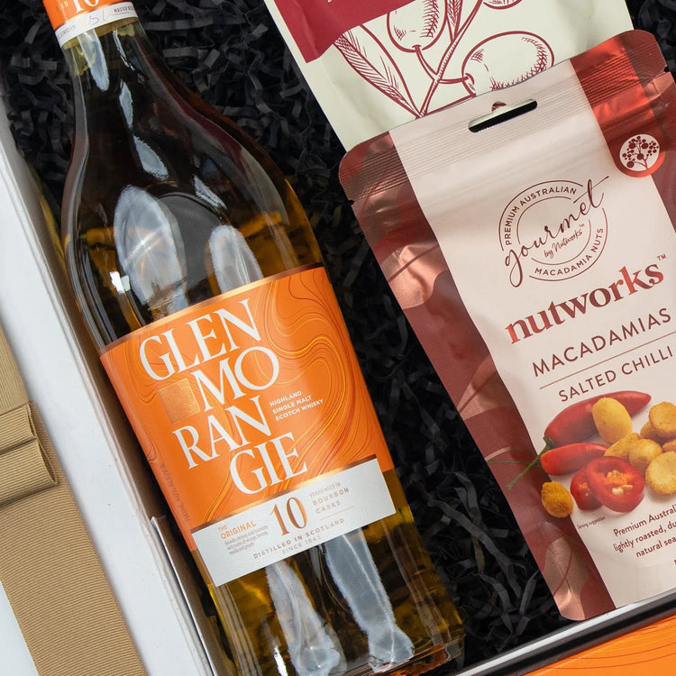 The Hamper Boutique Co's Glenmorangie Moments Hamper features Glenmorangie 10-year-old whisky with Nutworks salted chilli macadamias, elegantly presented on black shredded paper in a gift box.