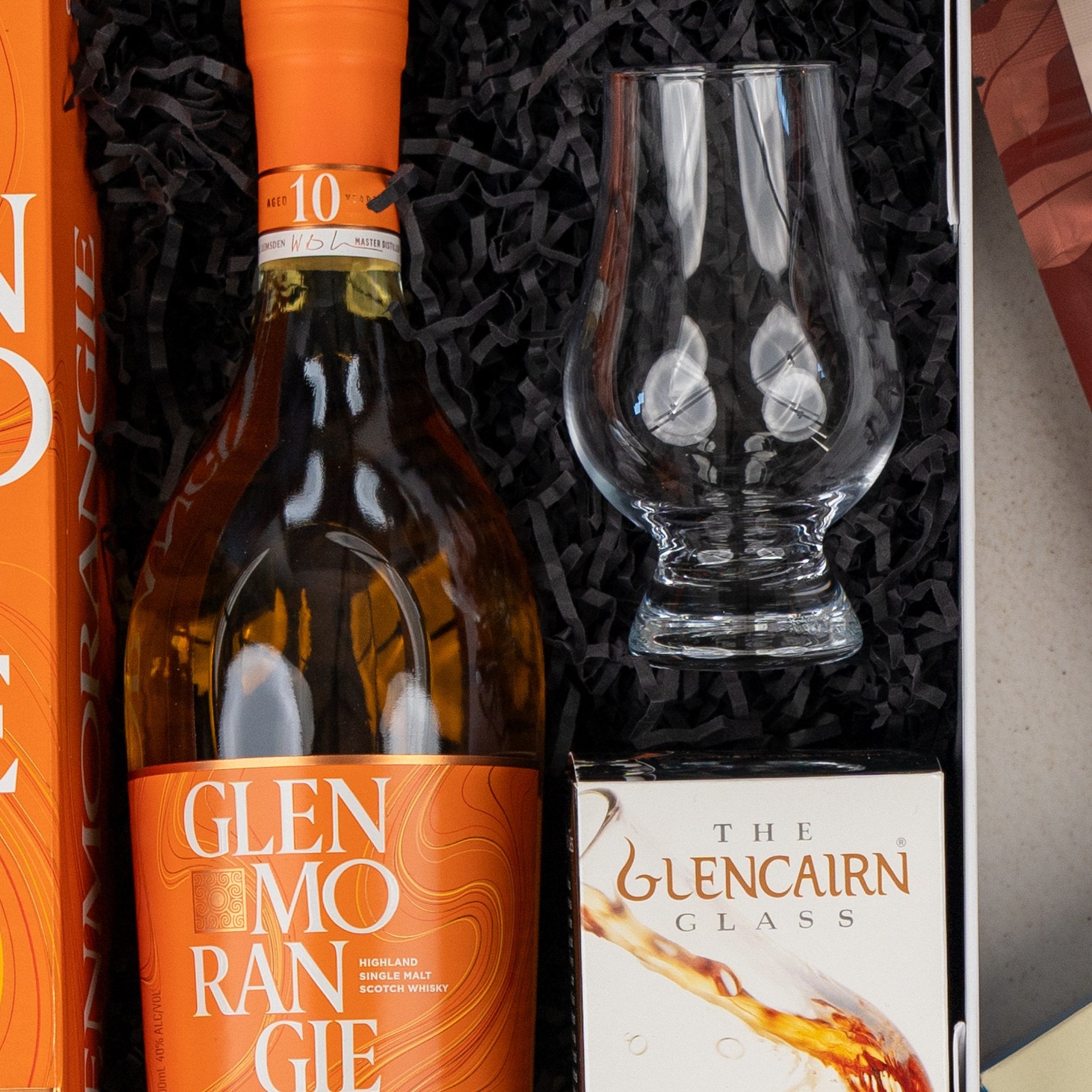 The Hamper Boutique Co Glenmorangie Discovery Hamper includes a bottle of Glenmorangie single malt Scotch, a Glencairn glass in its box, all presented within black shredded packing.