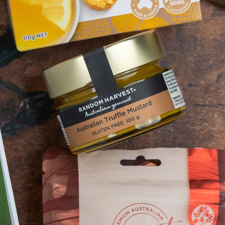 A Glenmorangie Premium Selection Hamper by The Hamper Boutique Co is set on a table with other packaged food items. The hamper label highlights its premium quality and is attractively presented for gifting.