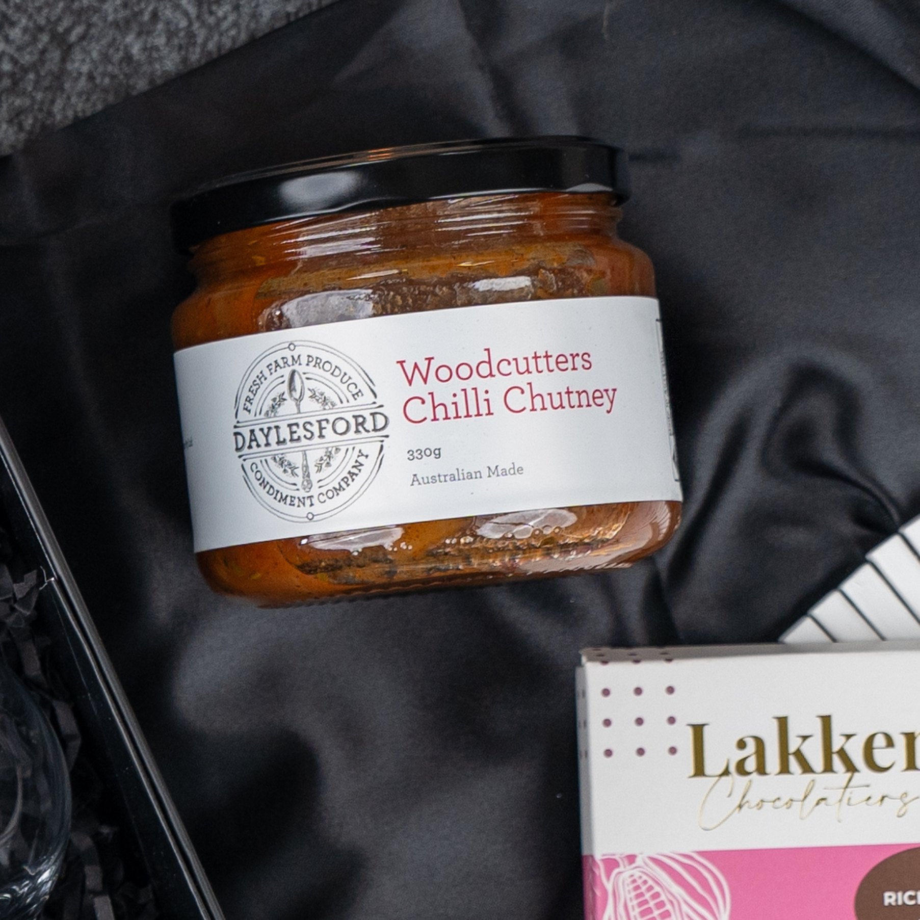 A box labeled Macallan Indulgence Hamper by The Hamper Boutique Co sits on a dark surface.