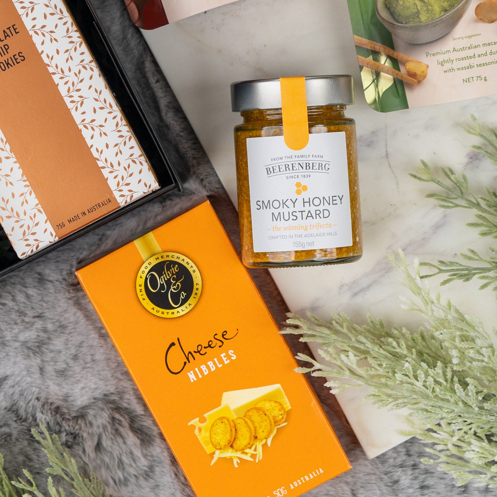The Tanqueray Gin Journey Hamper by The Hamper Boutique Co is displayed on a marble surface, accompanied by green foliage.