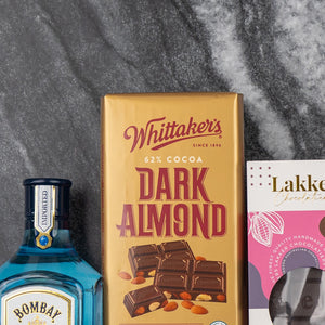 The Hamper Boutique Co's Bombay Sapphire Indulgence Hamper, featuring premium gin and exquisite chocolates, is elegantly arranged on a dark marble surface.