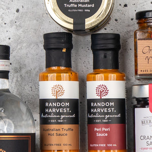 Close-up of The Hamper Boutique Co's Four Pillars Premium Gin Hamper, featuring assorted Australian gourmet products, including gin and condiments in jars and bottles.