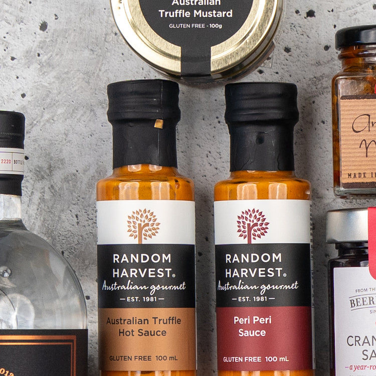 Close-up of The Hamper Boutique Co's Four Pillars Premium Gin Hamper, featuring assorted Australian gourmet products, including gin and condiments in jars and bottles.