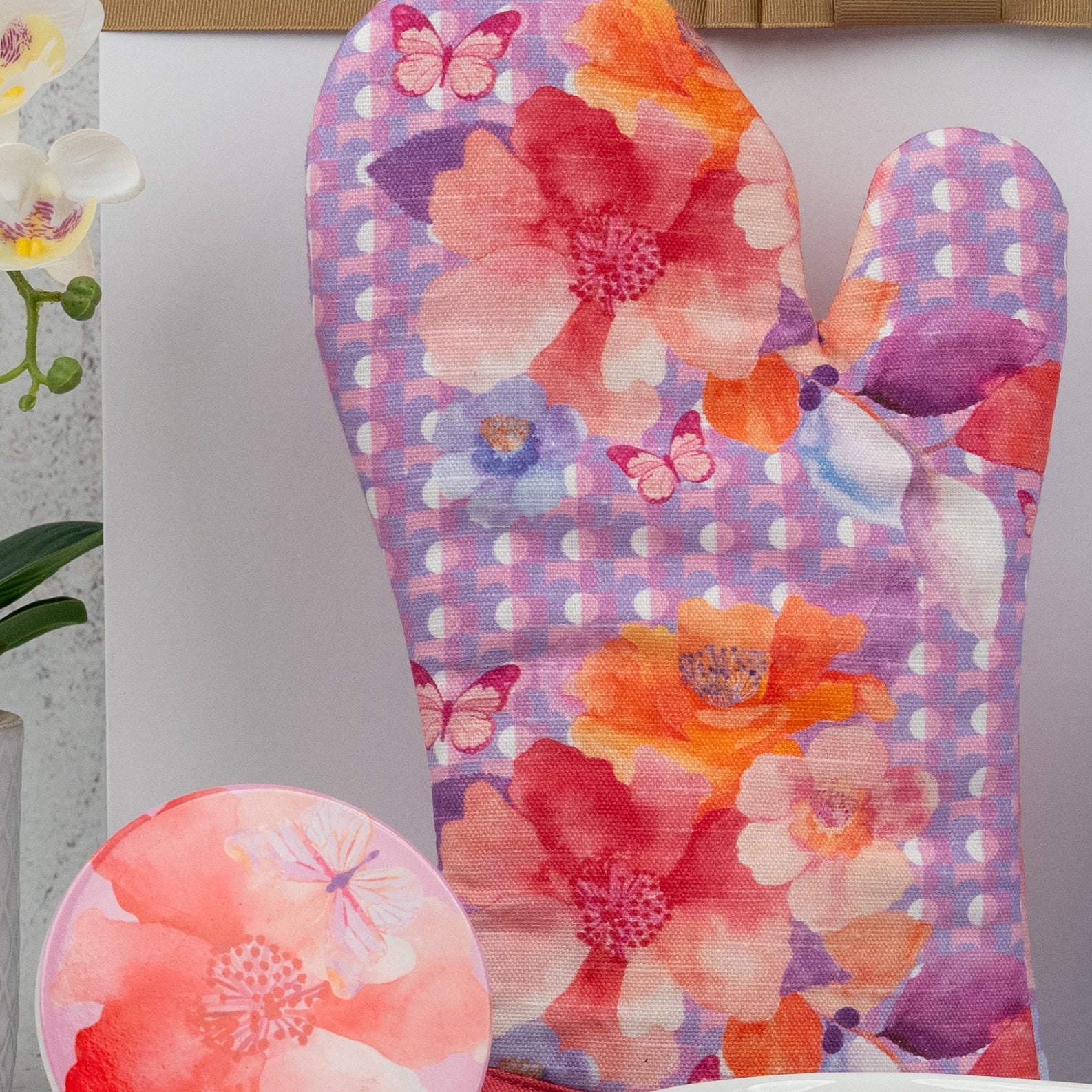 The Homeware Selection Hamper by The Hamper Boutique Co features a colorful oven mitt and matching plate with pink, orange, and purple floral patterns plus butterfly accents in a watercolor design.