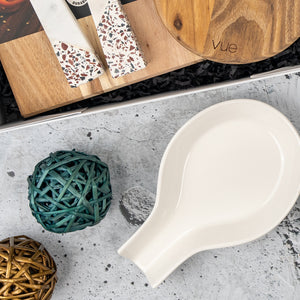 The Homeware Essentials Ensemble Hamper by The Hamper Boutique Co features a white ceramic spoon rest, teal and gold wicker balls, terrazzo-patterned coasters, and a round wooden board displayed on a gray textured surface.