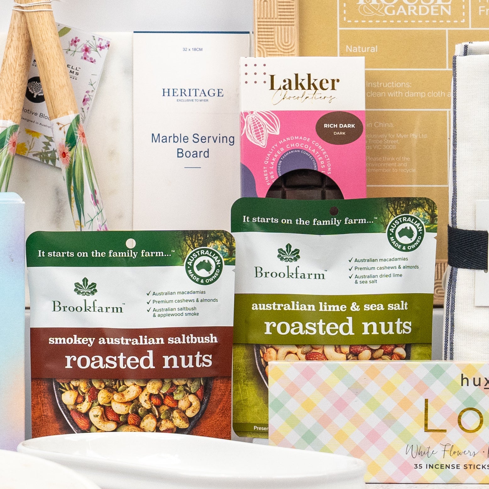 The Hamper Boutique Co’s Wellness and Homeware Hamper features Brookfarm roasted nuts, a Heritage marble serving board, incense sticks, and other decorative gifts carefully arranged together.