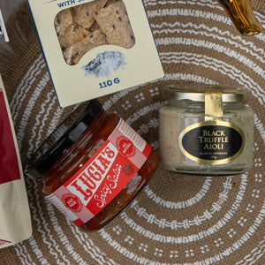 The Red Wine Gourmet Collection Hamper by The Hamper Boutique Co is arranged on a woven mat with a circular white pattern.