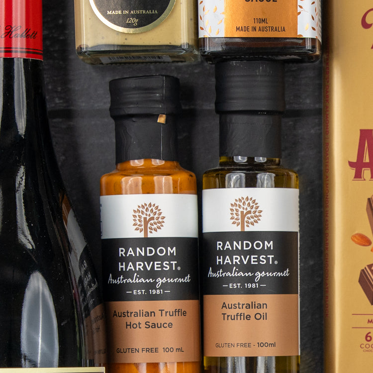 Close-up of The Hamper Boutique Co Luxury Indulgence Gift Hamper featuring truffle hot sauce, truffle oil, gourmet mustard, and a chocolate bar, all stylishly displayed in a gift box.