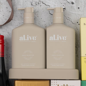Two beige bottles from The Hamper Boutique Co’s Indulgent Evening Escape sit side by side in a matching tray—hand & body lotion on the left, hand & body wash on the right. Both bottles feature minimal text and a modern, neutral design.