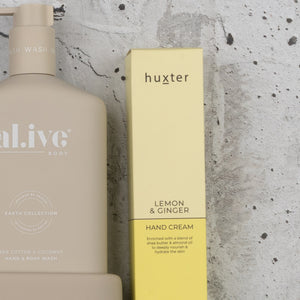 The Hamper Boutique Co's Indulgent Evening Escape features a beige body wash bottle and a yellow hand cream box, displayed side by side against a speckled gray background.