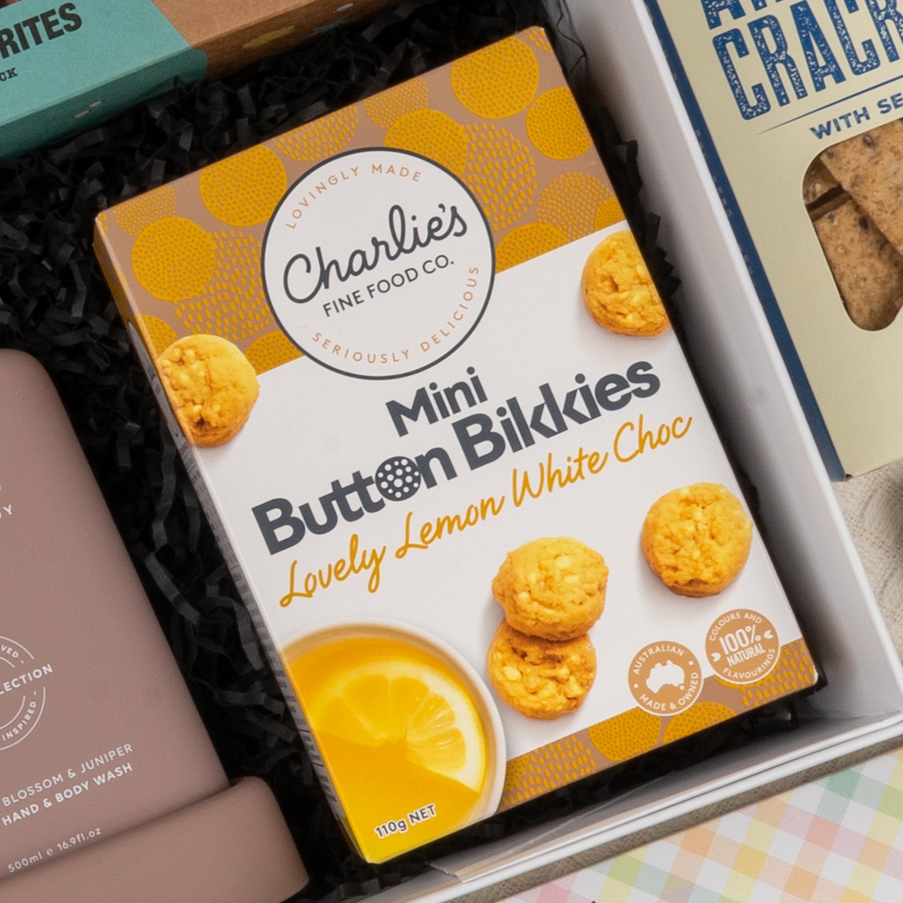 A Deluxe Wine and Relaxation Hamper by The Hamper Boutique Co is displayed in a gift box, featuring its yellow and white packaging with relaxing themed images.