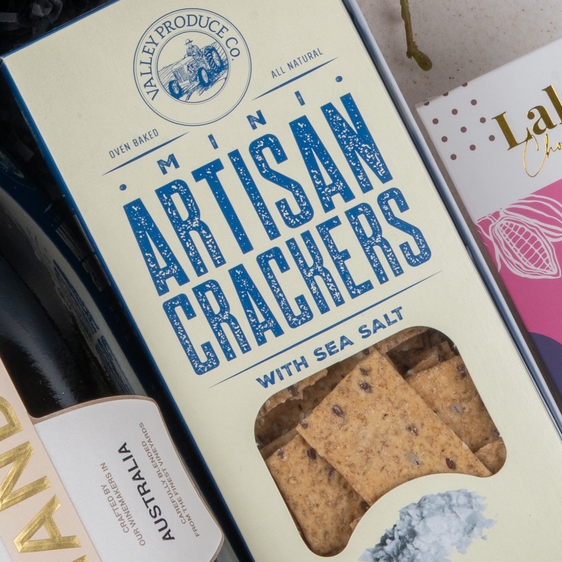A Chandon Celebration Hamper from The Hamper Boutique Co is shown close up, featuring a cream-colored package and bold blue label text, with contents visible through a clear window.