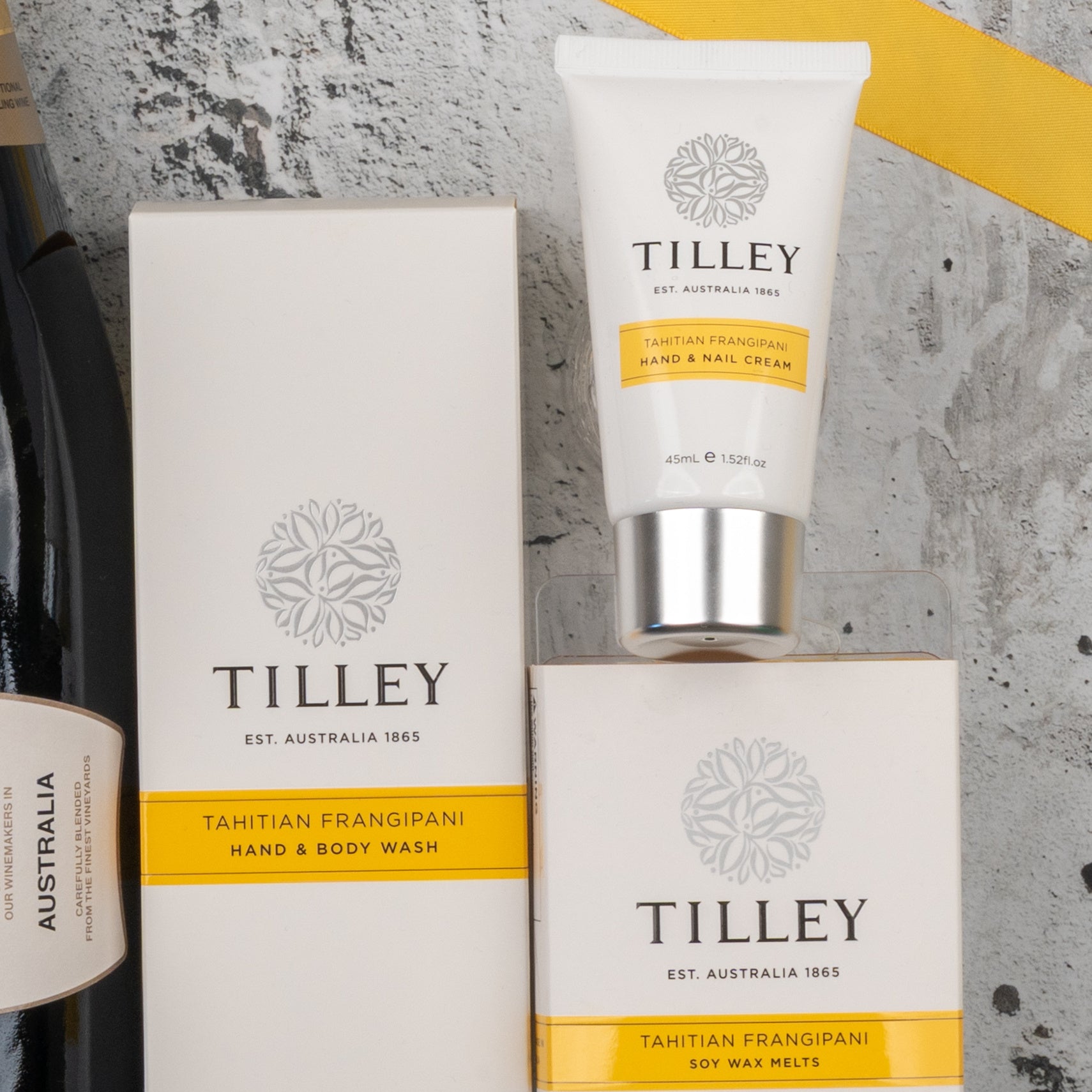 The Chandon Bubbles and Treats Hamper from The Hamper Boutique Co is displayed on a gray textured surface with yellow accents and a partial view of a wine bottle.