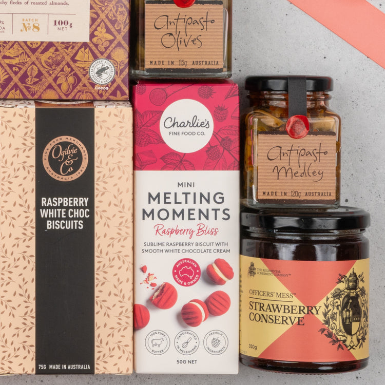 A close-up of The Hamper Boutique Co’s Chandon Rosé Deluxe Celebration Hamper, featuring raspberry biscuits, mini melting moments, olives, antipasto medley, and strawberry conserve in vibrant boxes and jars, arranged neatly together.