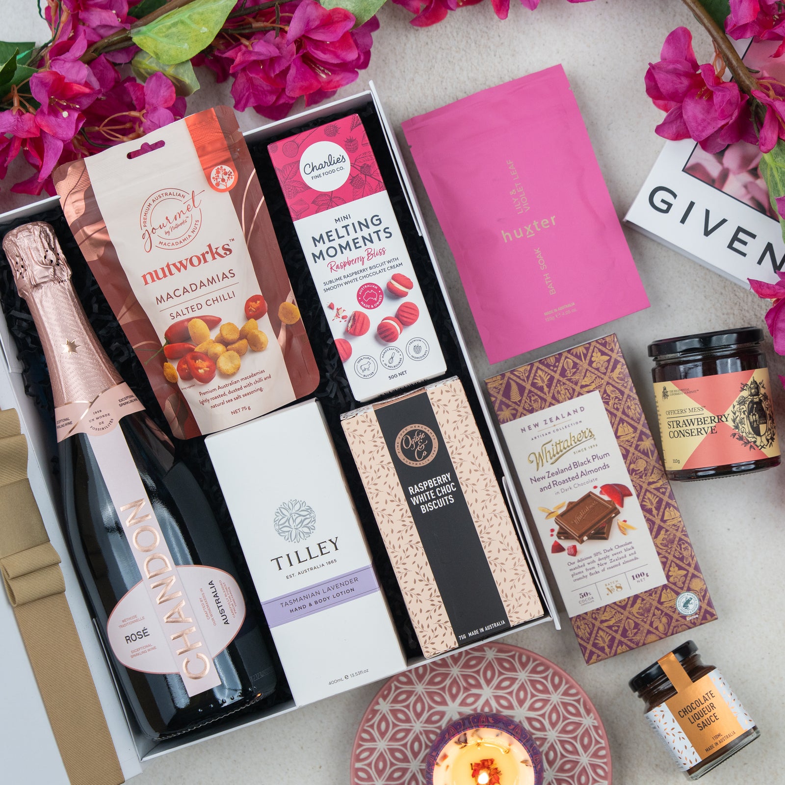 The Hamper Boutique Co’s Chandon Rosé Luxury Selection Hamper includes Chandon rosé, gourmet snacks, chocolates, cookies, a candle, and beauty products—beautifully presented with pink flowers and a pink "Given" gift card.