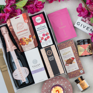 The Hamper Boutique Co’s Chandon Rosé Luxury Selection Hamper includes Chandon rosé, gourmet snacks, chocolates, cookies, a candle, and beauty products—beautifully presented with pink flowers and a pink "Given" gift card.