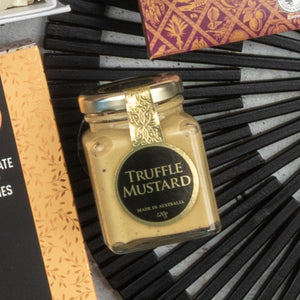 A Moët & Chandon Deluxe Celebration Hamper by The Hamper Boutique Co is displayed on a dark textured surface, surrounded by its patterned packaging.